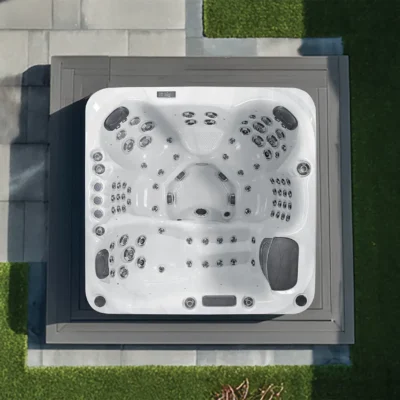 Top-down view of a white outdoor hot tub with many jets on a gray deck.
