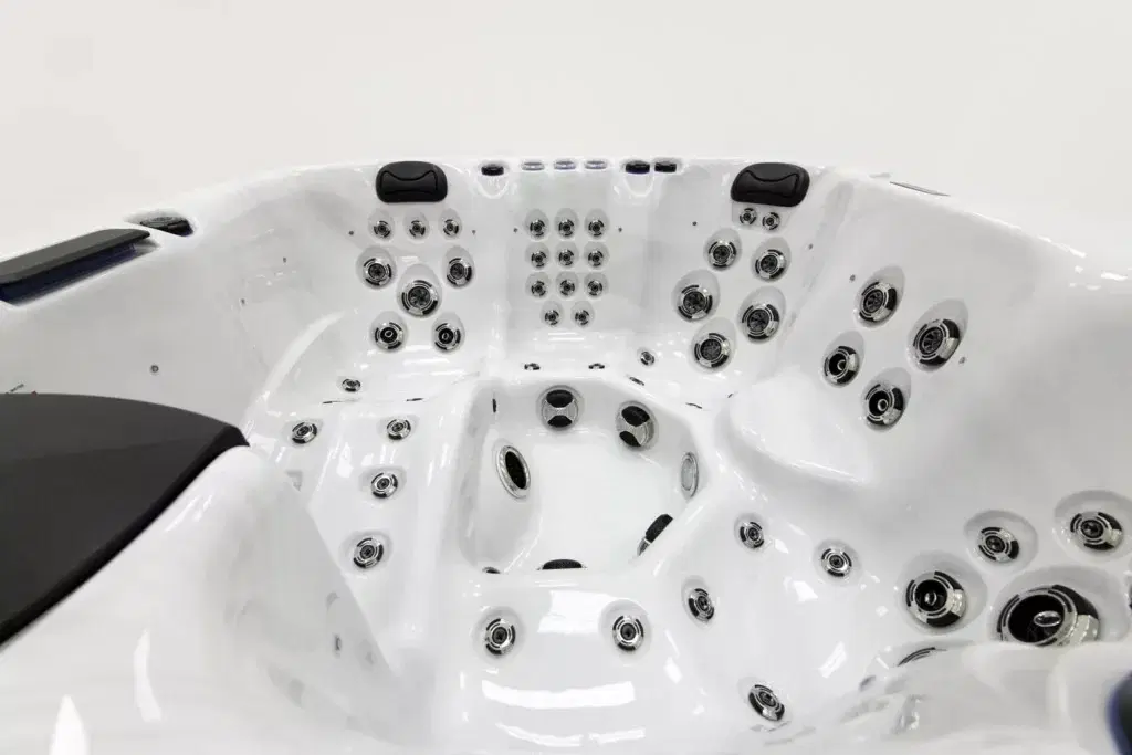 White acrylic hot tub with multiple chrome jets and black headrests, showcasing a spacious interior with seating areas.