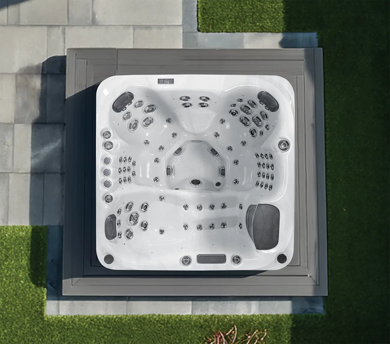 Top-down view of a white outdoor hot tub with many jets on a gray deck.