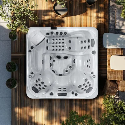 Top-down view of a white hot tub on a wooden deck surrounded by plants and outdoor seating.
