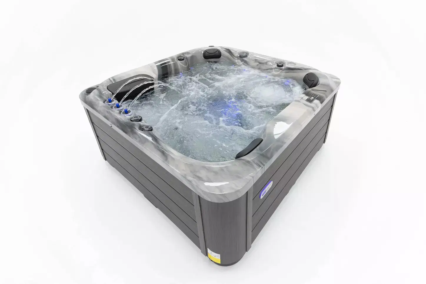 Gray outdoor hot tub with bubbling water and multiple jet seats/speakers.