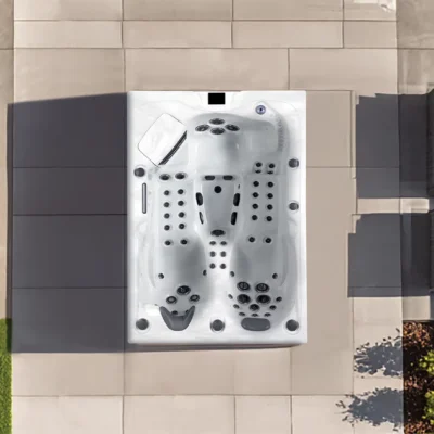Top-down view of a white rectangular hot tub with many jets on a tiled outdoor patio.